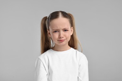 Portrait of sad girl on light grey background