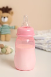 Feeding bottle with milk on white table