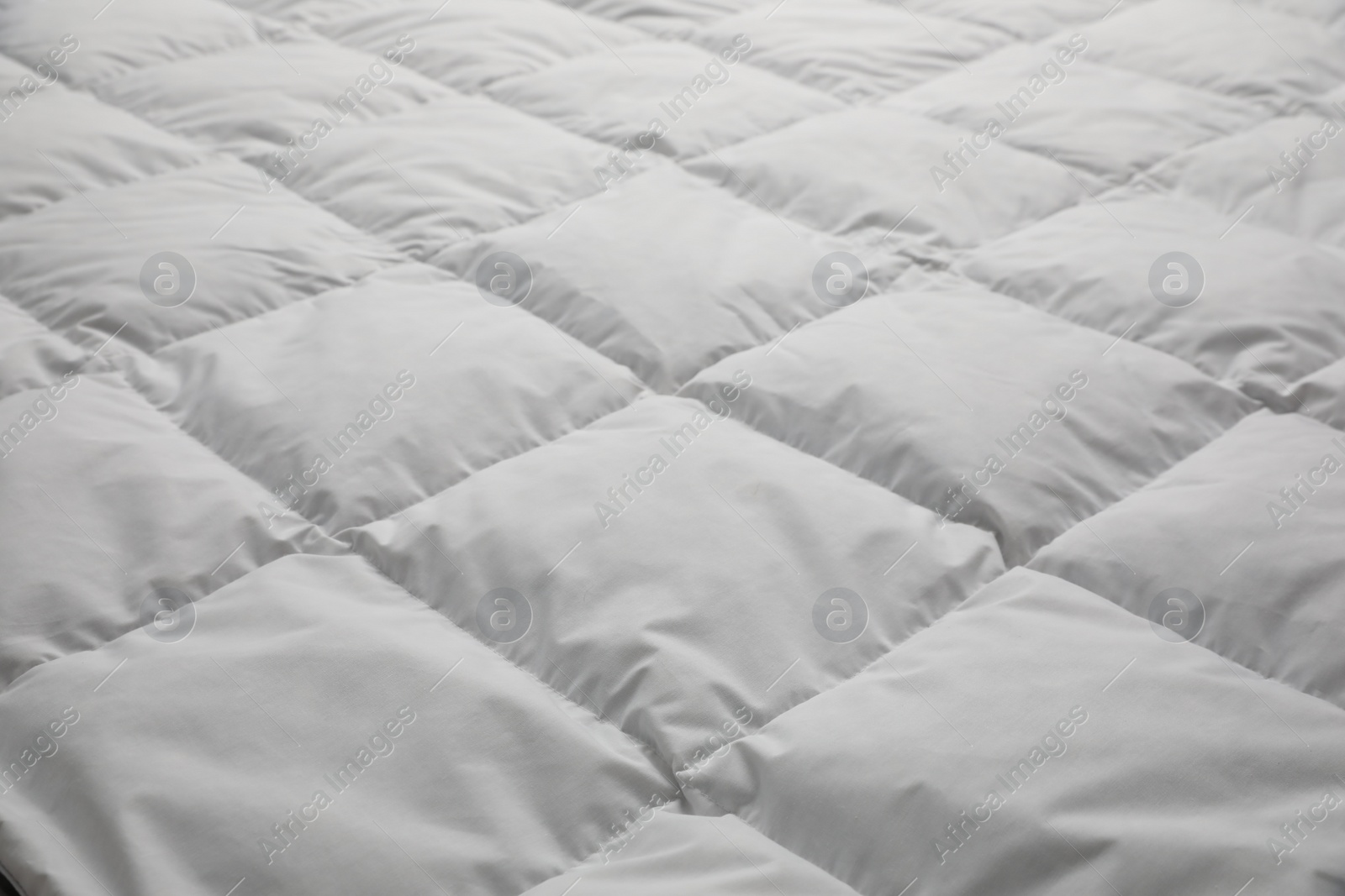 Photo of Soft quilted blanket as background, closeup view