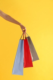 Photo of Woman with paper shopping bags on yellow background, closeup