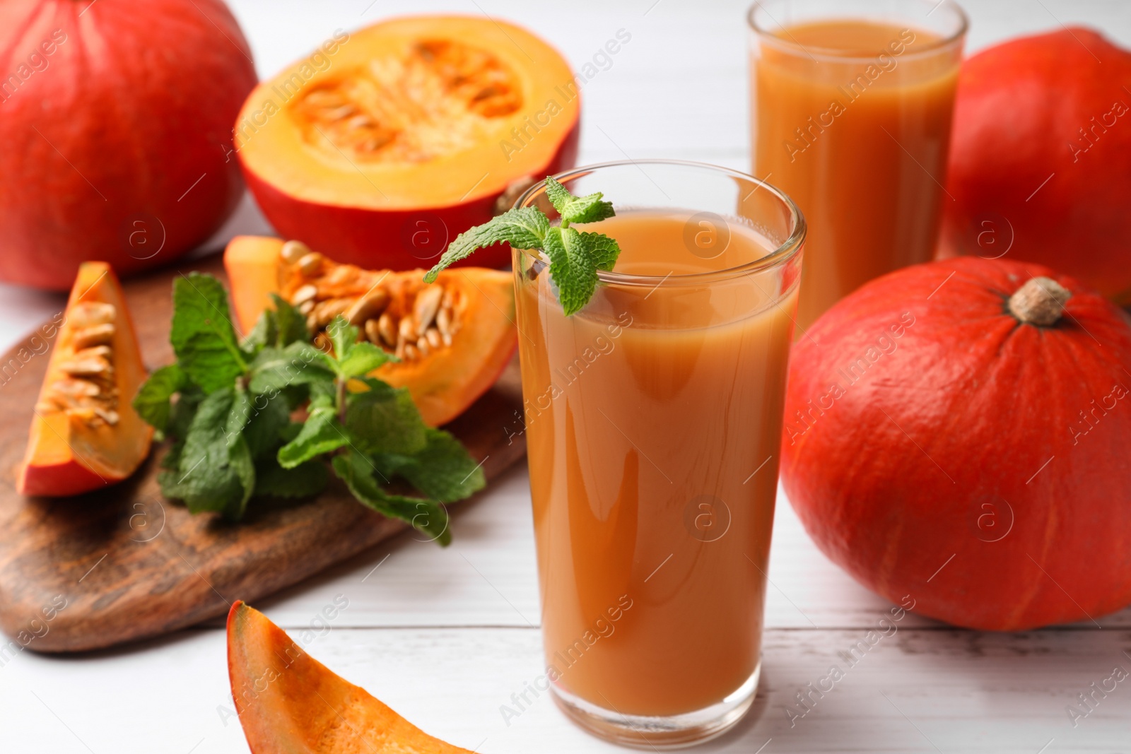 Photo of Tasty pumpkin juice and pumpkins on white wooden table