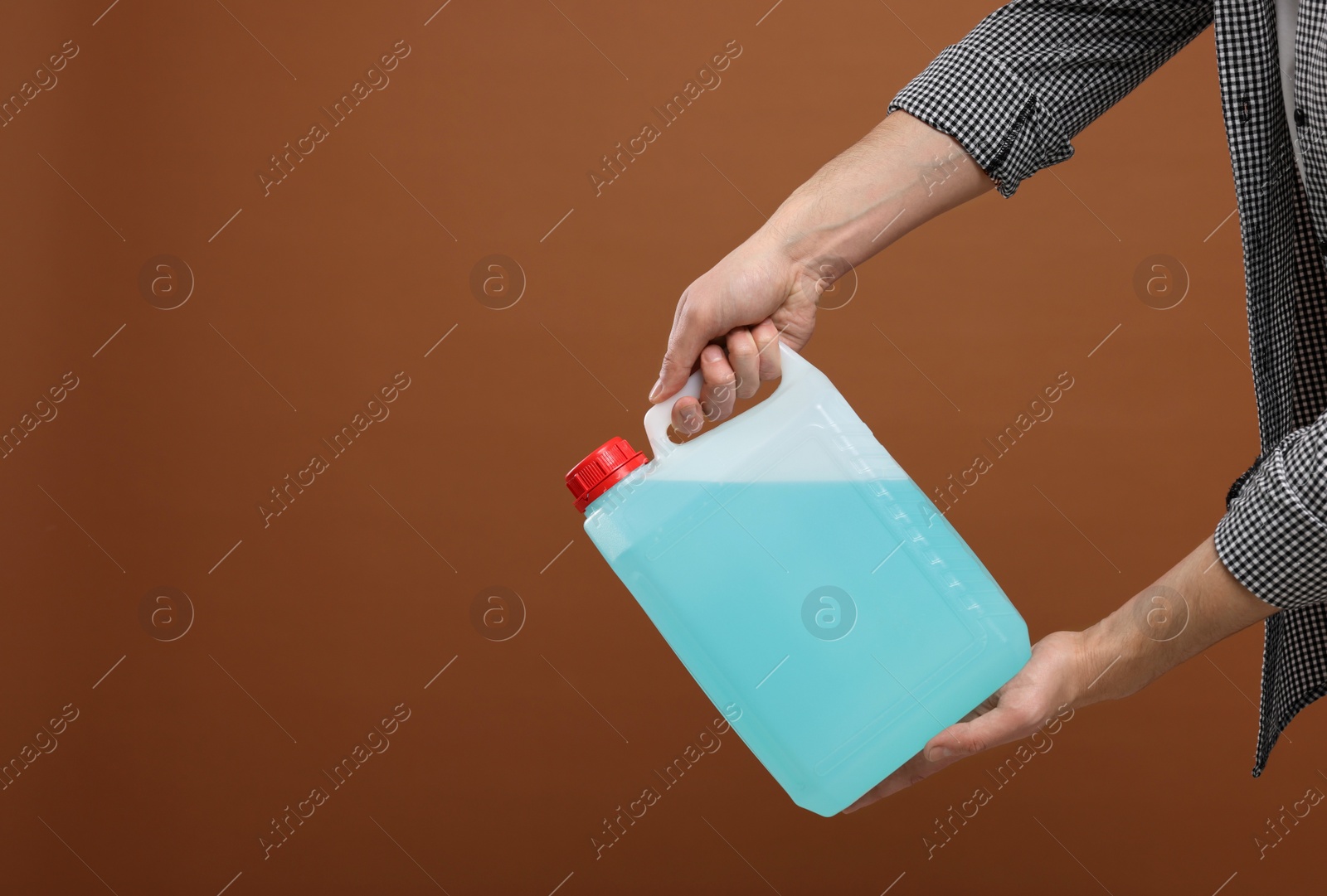 Photo of Man holding canister with blue liquid on brown background, closeup. Space for text