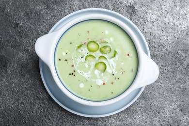Photo of Bowl of delicious asparagus soup on grey table, top view