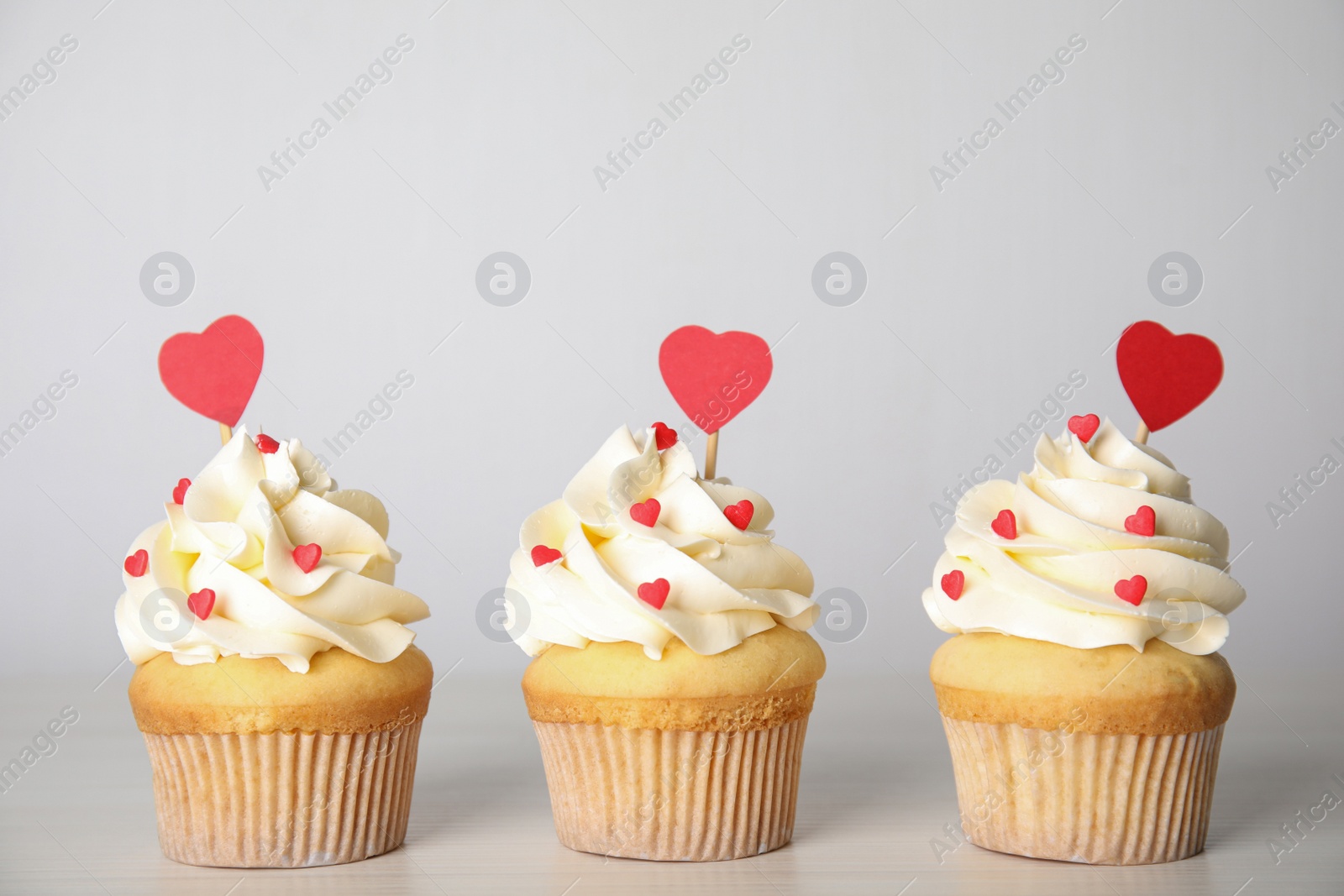 Photo of Tasty sweet cupcakes on white table. Happy Valentine's Day