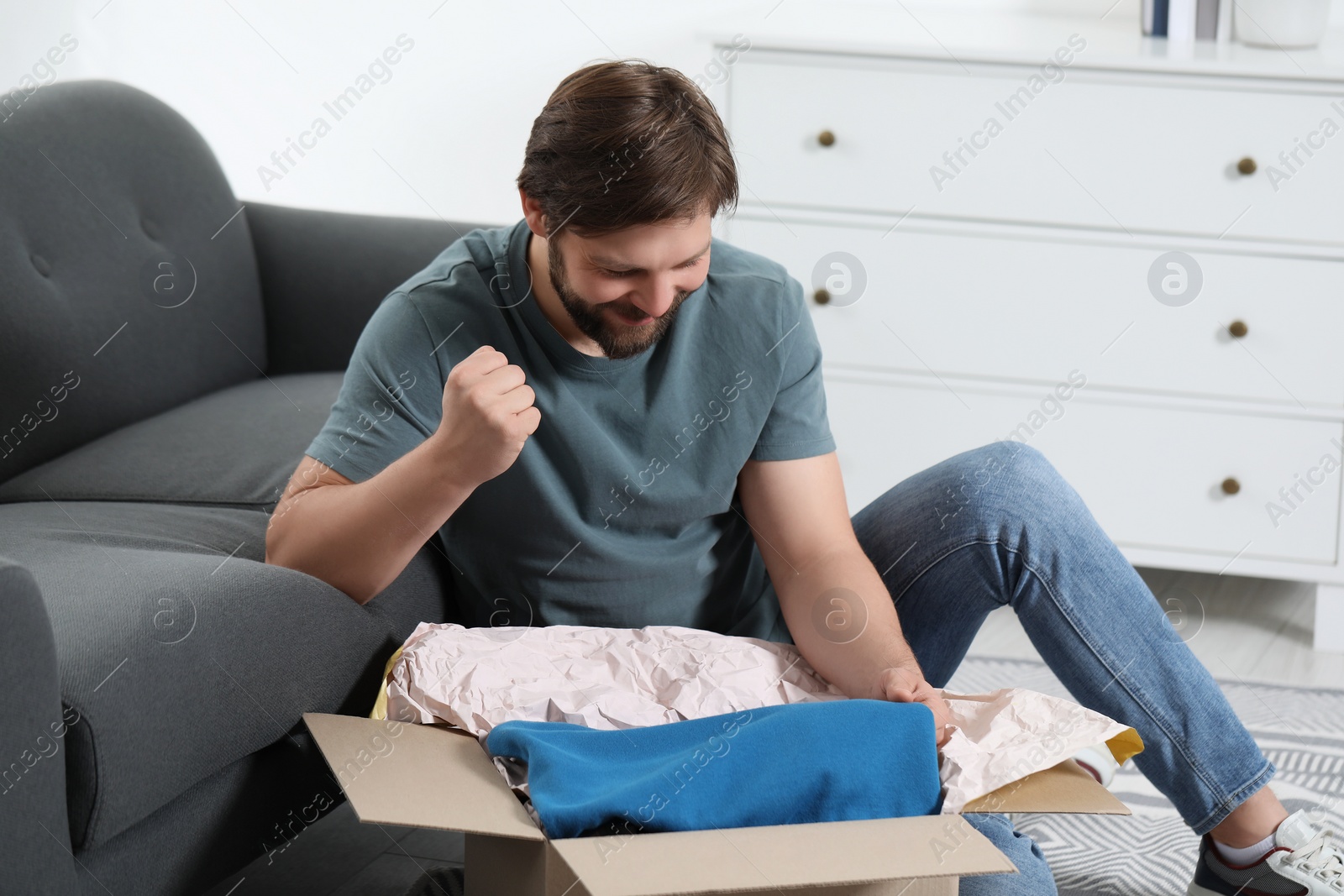 Photo of Happy man opening parcel at home. Internet shopping