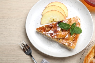 Slice of traditional apple pie served on wooden table, flat lay