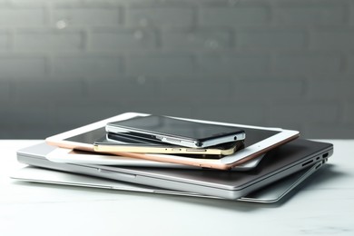 Photo of Stack of electronic devices on white table, closeup. Space for text