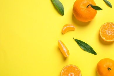 Photo of Flat lay composition with fresh ripe tangerines and leaves on yellow background, space for text. Citrus fruit