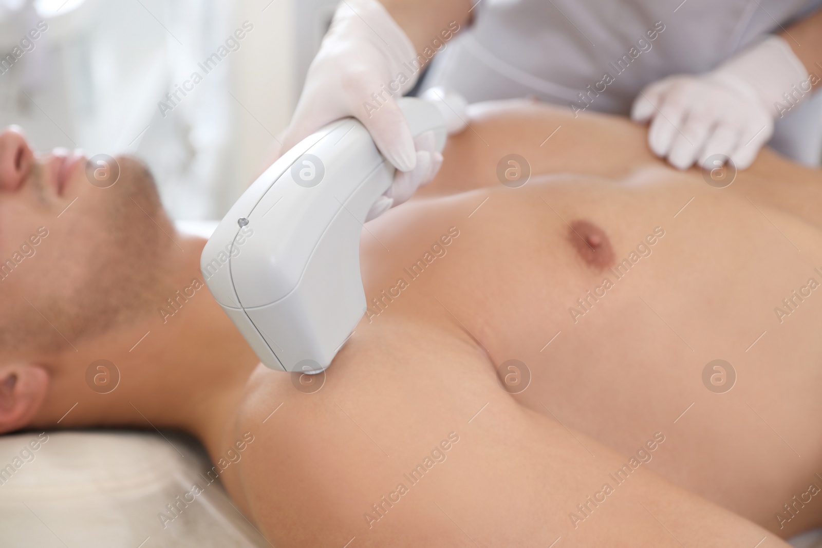 Photo of Young man undergoing laser epilation procedure in beauty salon, closeup