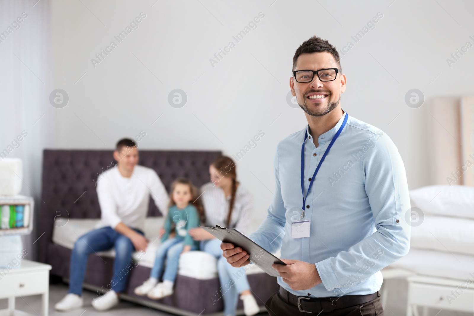 Photo of Happy salesman and his clients in mattress store