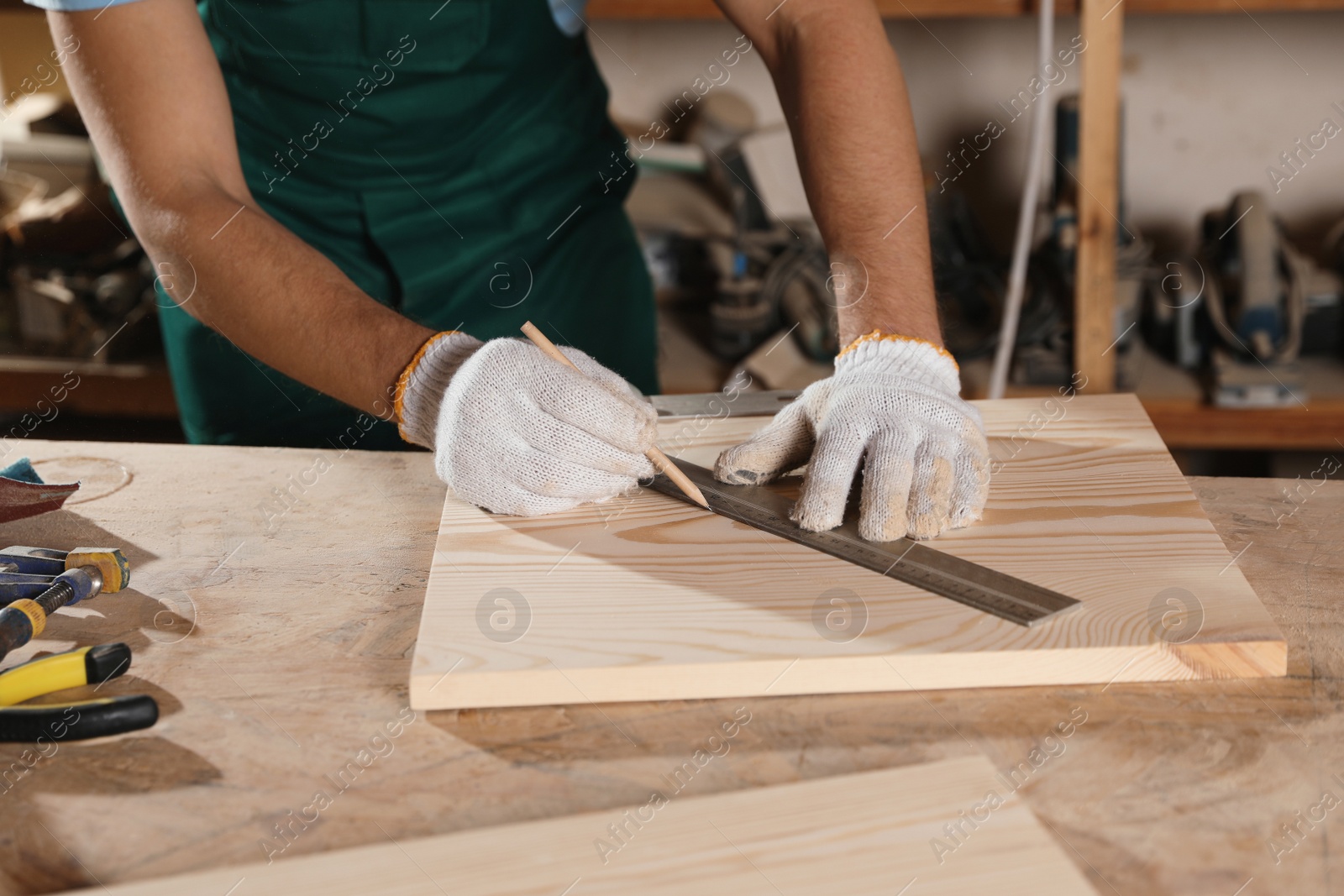 Photo of Professional carpenter measuring wooden board in workshop, closeup