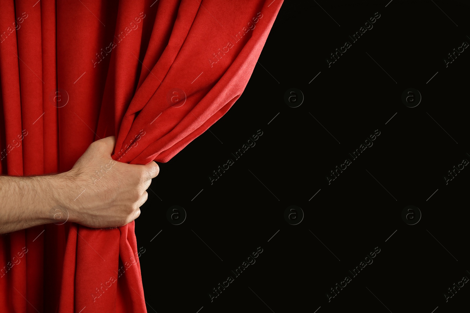 Photo of Man opening red front curtains on black background, closeup. Space for text