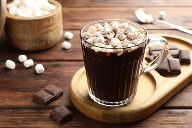 Photo of Cup of aromatic hot chocolate with marshmallows and cocoa powder served on wooden table, closeup