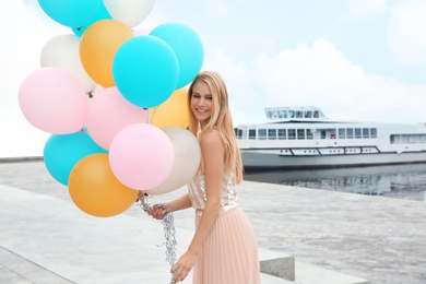 Photo of Beautiful young woman with bunch of balloons outdoors