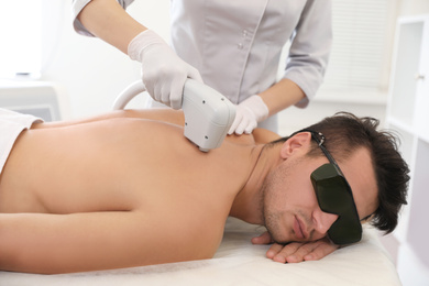 Young man undergoing laser epilation procedure in beauty salon