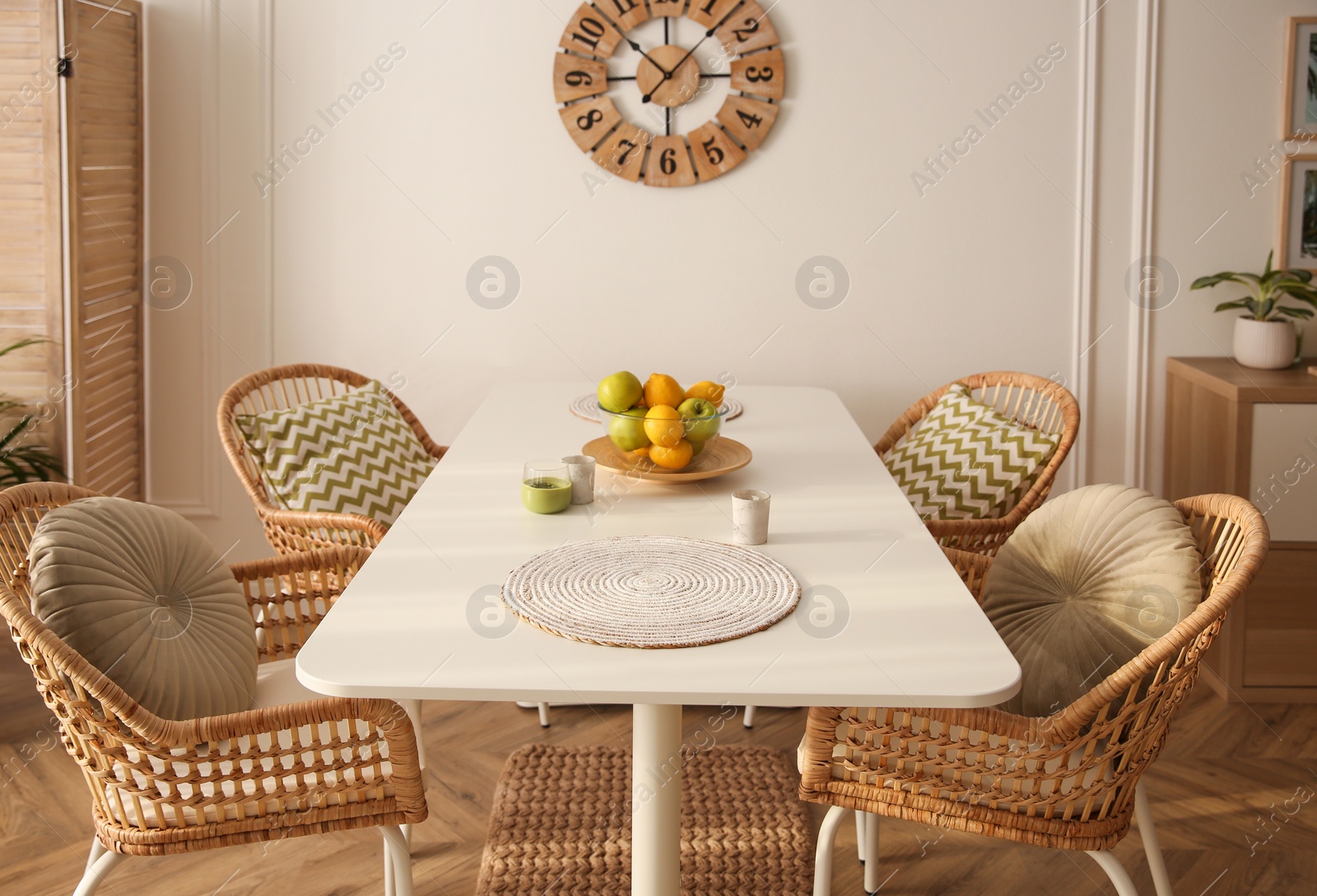 Photo of Stylish white dining table and wicker chairs in room. Interior design