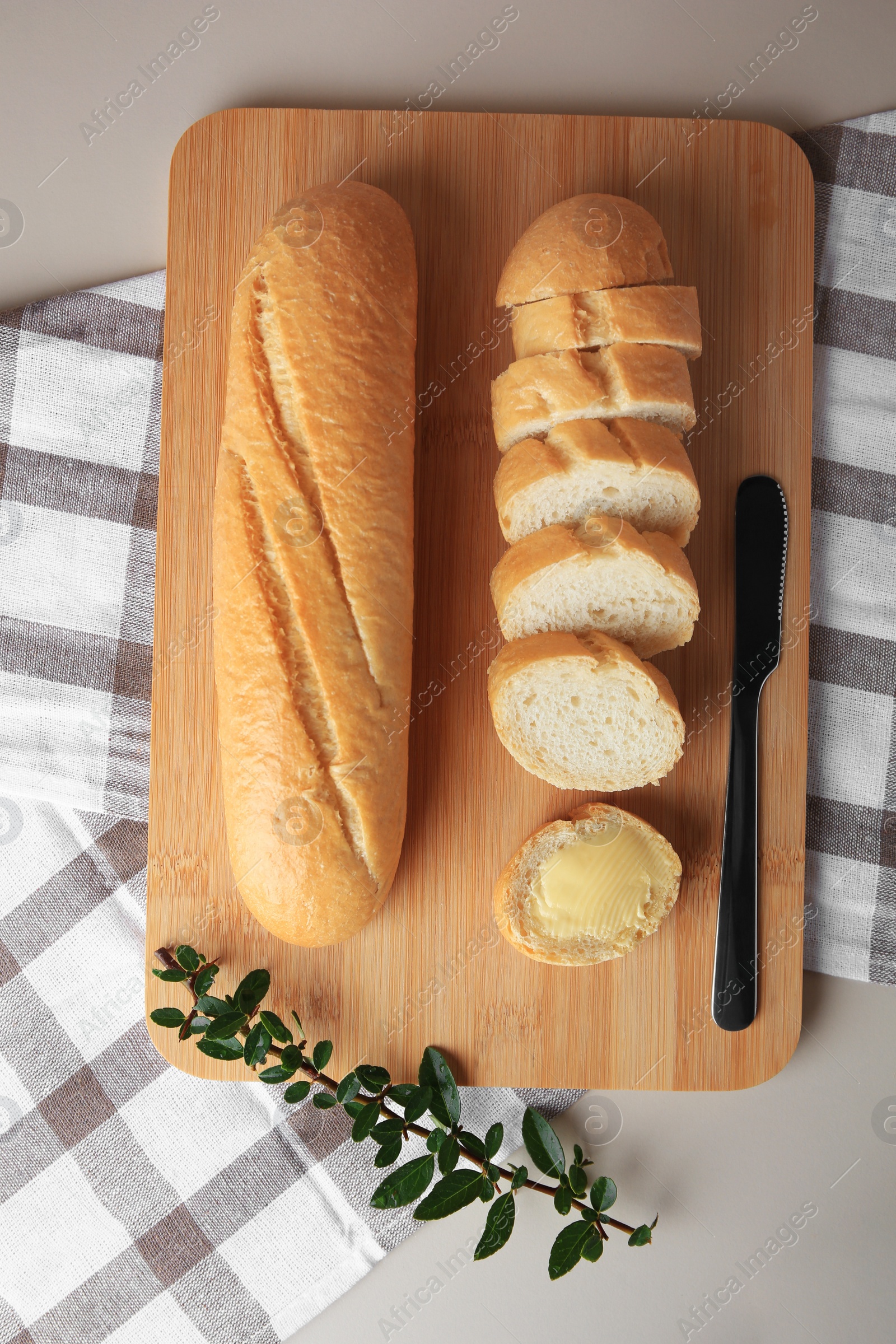 Photo of Whole and cut baguettes with fresh butter on table, flat lay