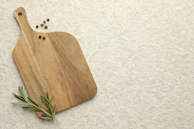 Photo of Cutting board, pepper and rosemary on white textured table, flat lay. Space for text