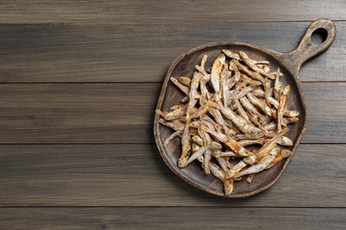 Photo of Serving board with tasty dried anchovies on wooden table, top view. Space for text