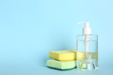 Photo of Cleaning product and sponges on light blue background, space for text. Dish washing supplies