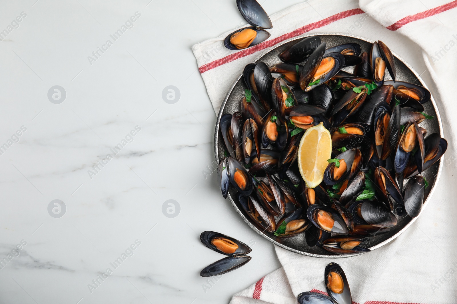 Photo of Plate with cooked mussels, parsley and lemon on white marble table, flat lay. Space for text