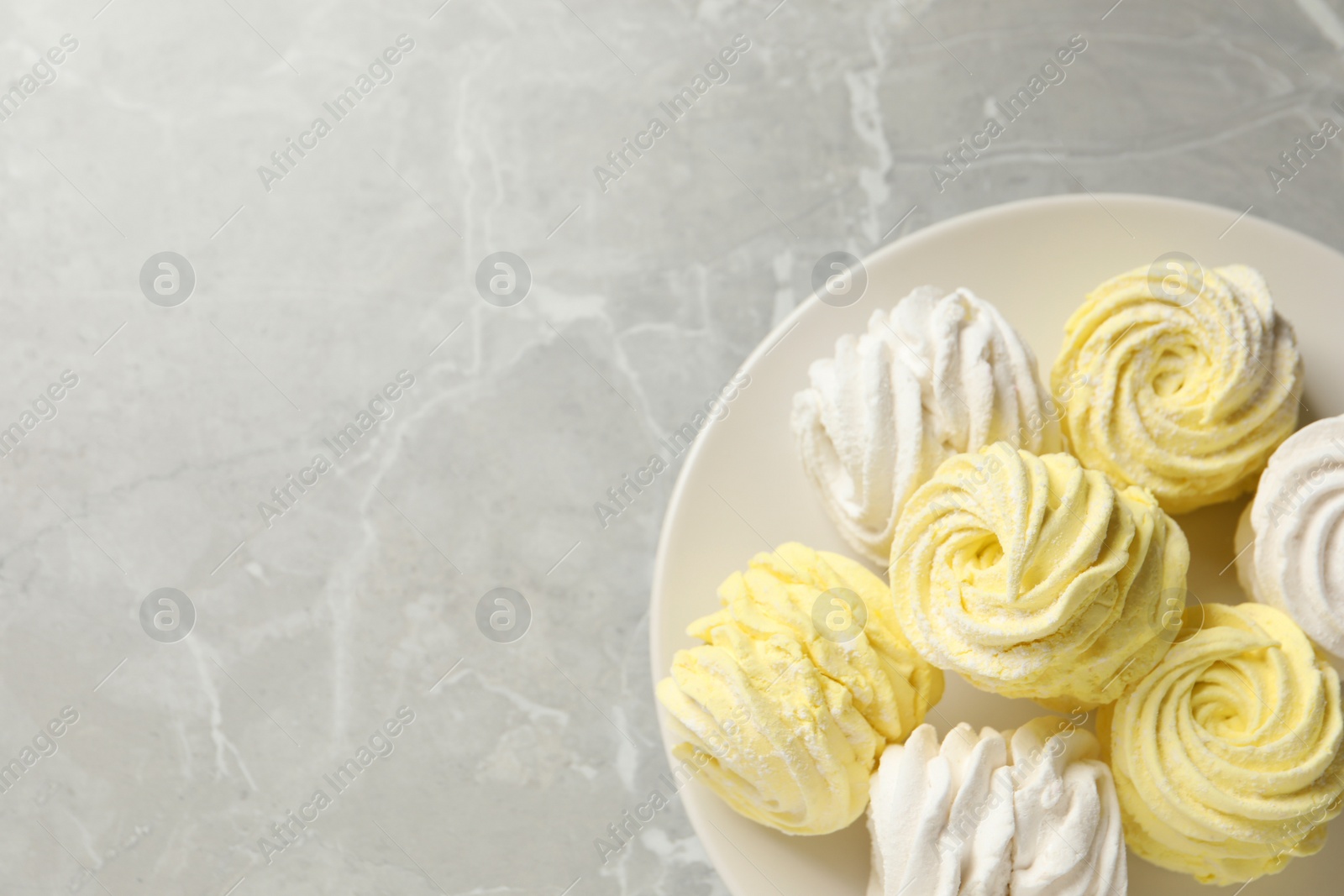 Photo of Delicious white and yellow marshmallows on grey marble table, top view. Space for text