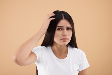 Photo of Woman examining her hair and scalp on beige background. Dandruff problem