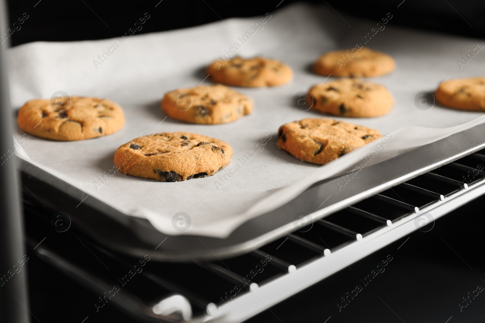 Photo of Baking delicious chocolate chip cookies in oven, closeup