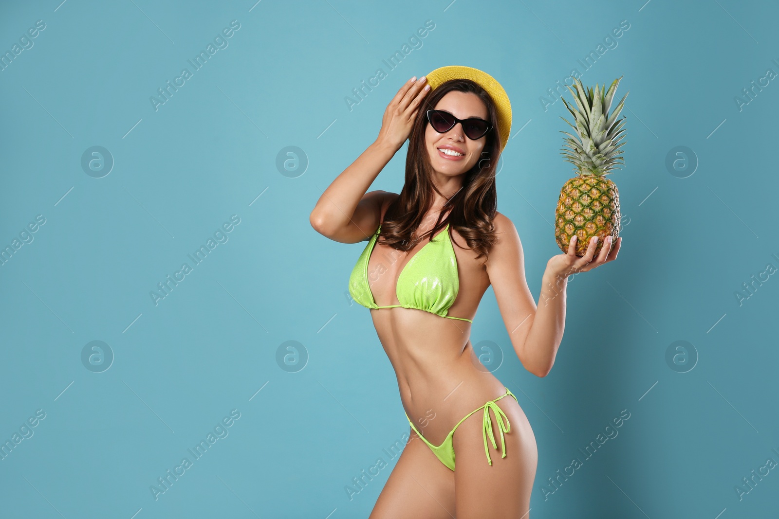 Photo of Beautiful woman in stylish bikini with pineapple on blue background. Space for text