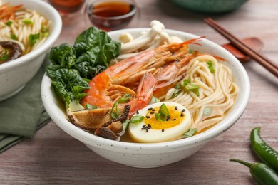 Photo of Delicious ramen with shrimps and egg in bowl on wooden table, closeup. Noodle soup