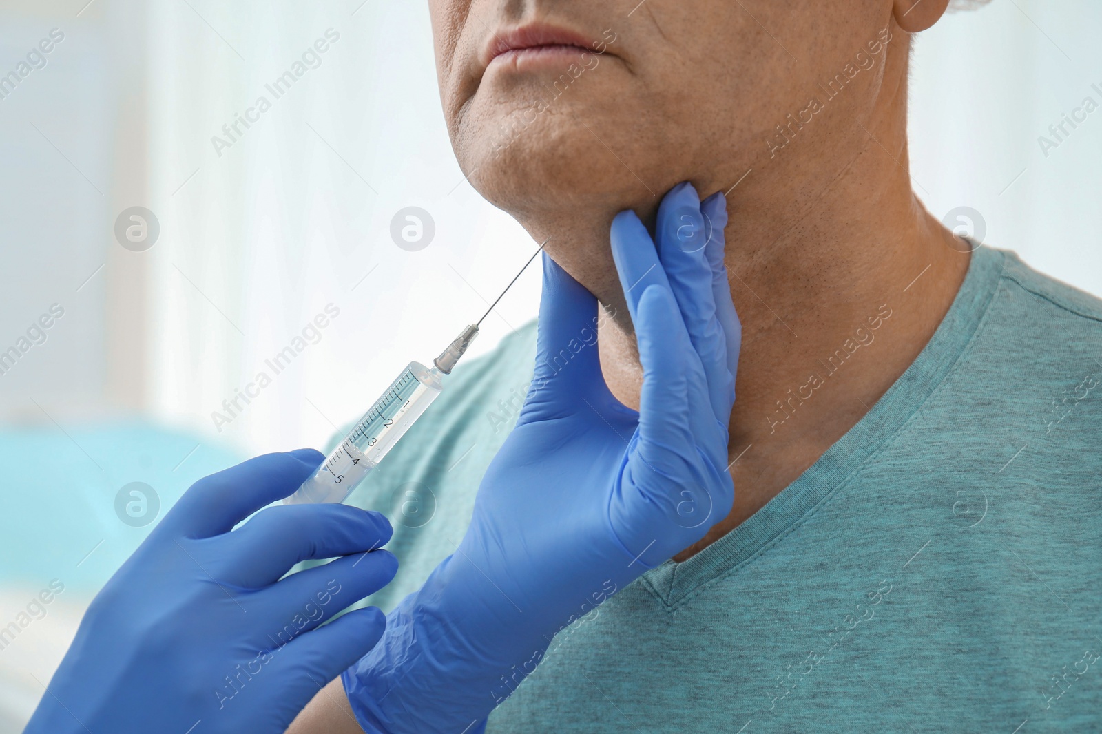 Photo of Mature man with double chin receiving injection in clinic, closeup