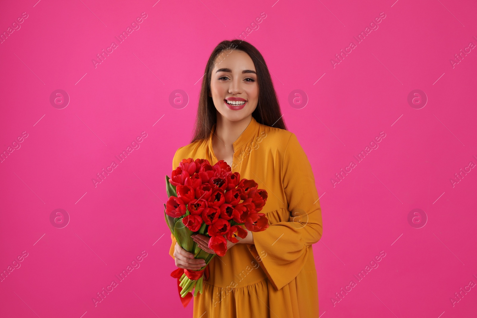 Photo of Happy woman with red tulip bouquet on pink background. 8th of March celebration