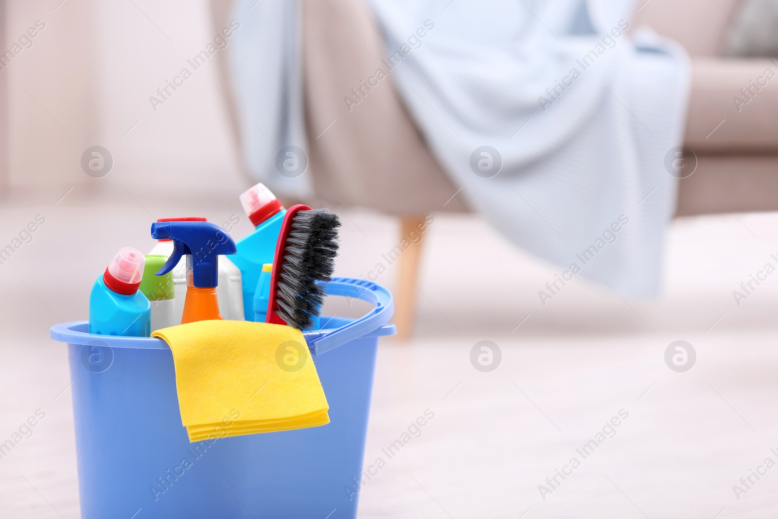 Photo of Bucket with cleaning supplies on floor indoors. Space for text