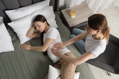 Photo of Doula working with pregnant woman in bedroom, top view. Preparation for child birth