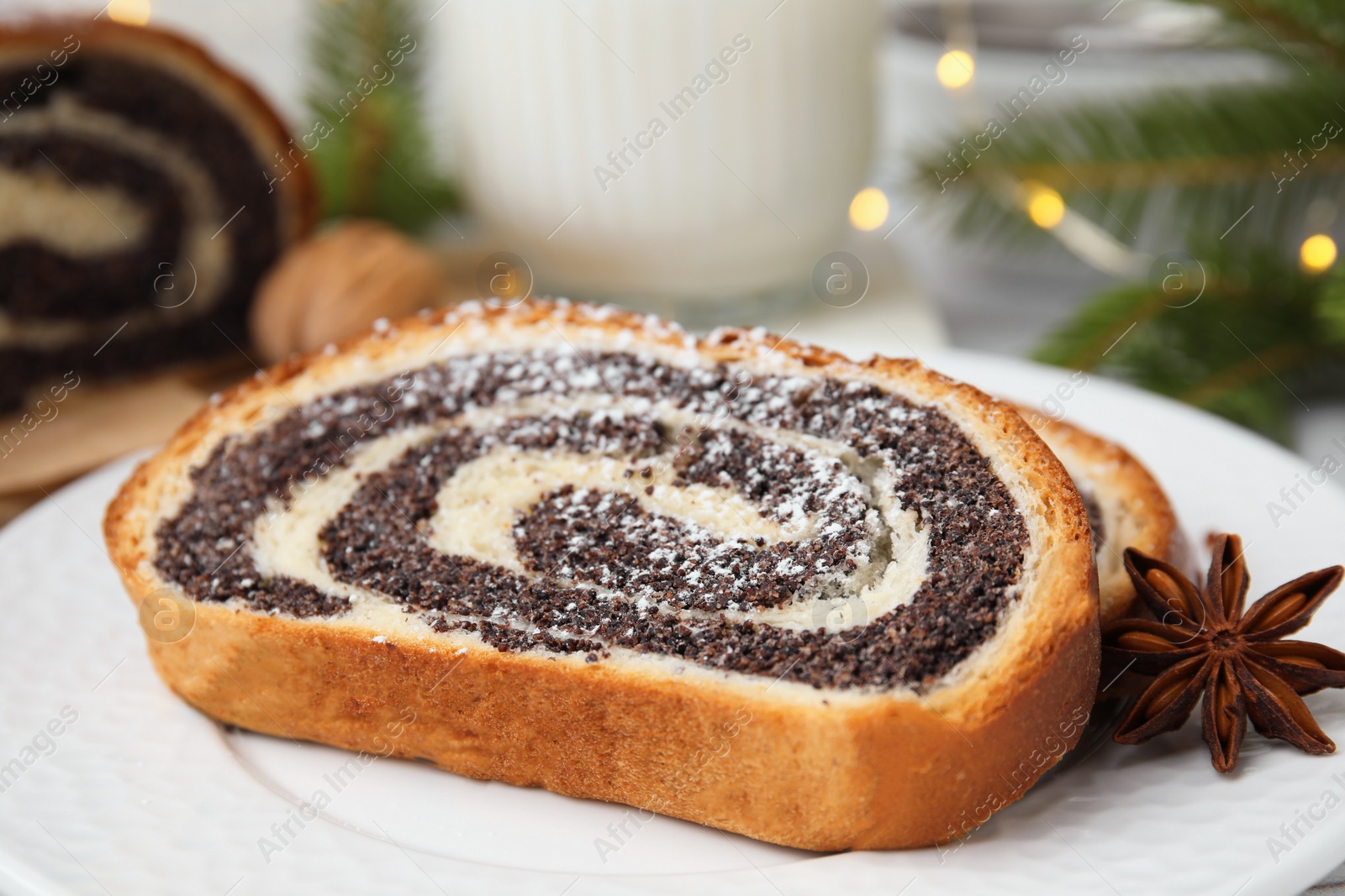 Photo of Slice of poppy seed roll and anise star on plate, closeup. Tasty cake