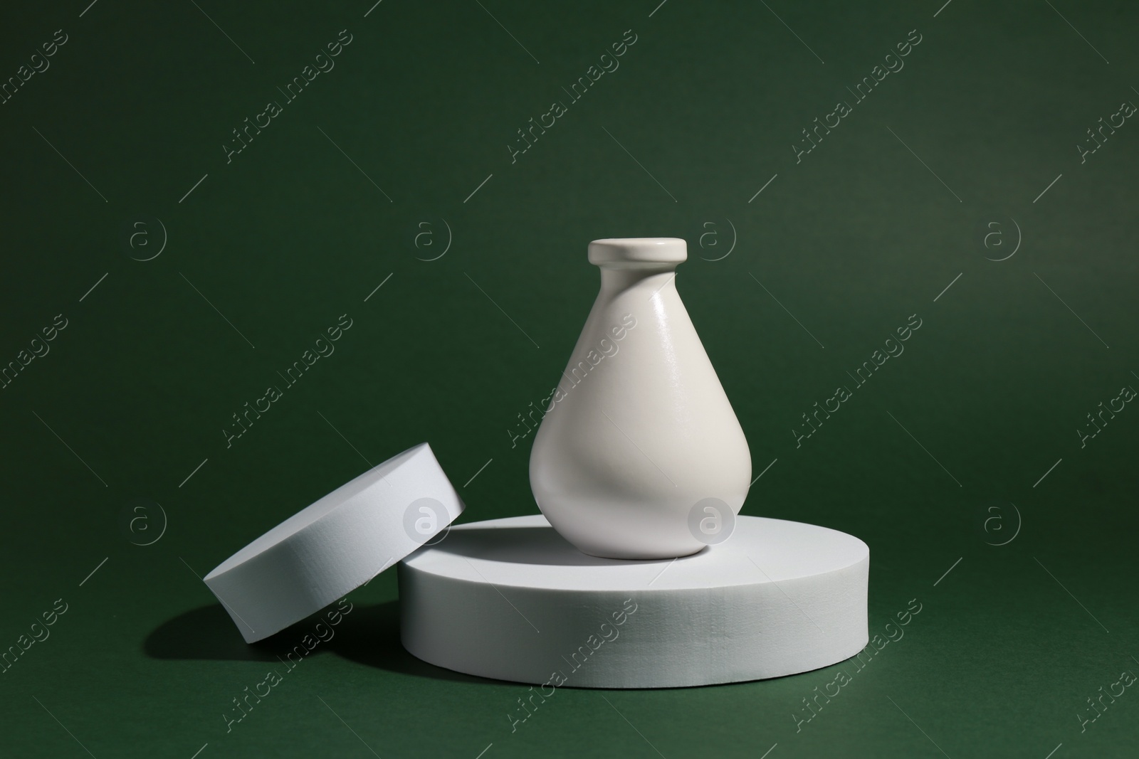 Photo of Product photography props. Round shaped podiums and vase on green background
