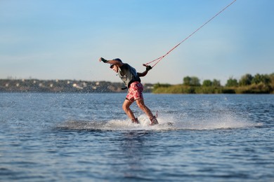 Photo of Teenage boy wakeboarding on river. Extreme water sport