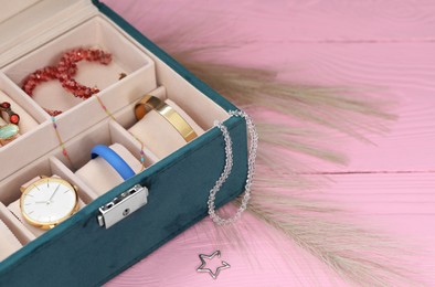 Jewelry box with many different accessories on pink wooden table, closeup. Space for text
