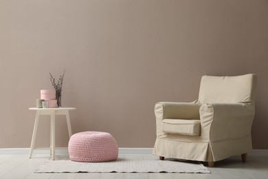 Stylish room interior with pouf, armchair and decor elements. Space for text