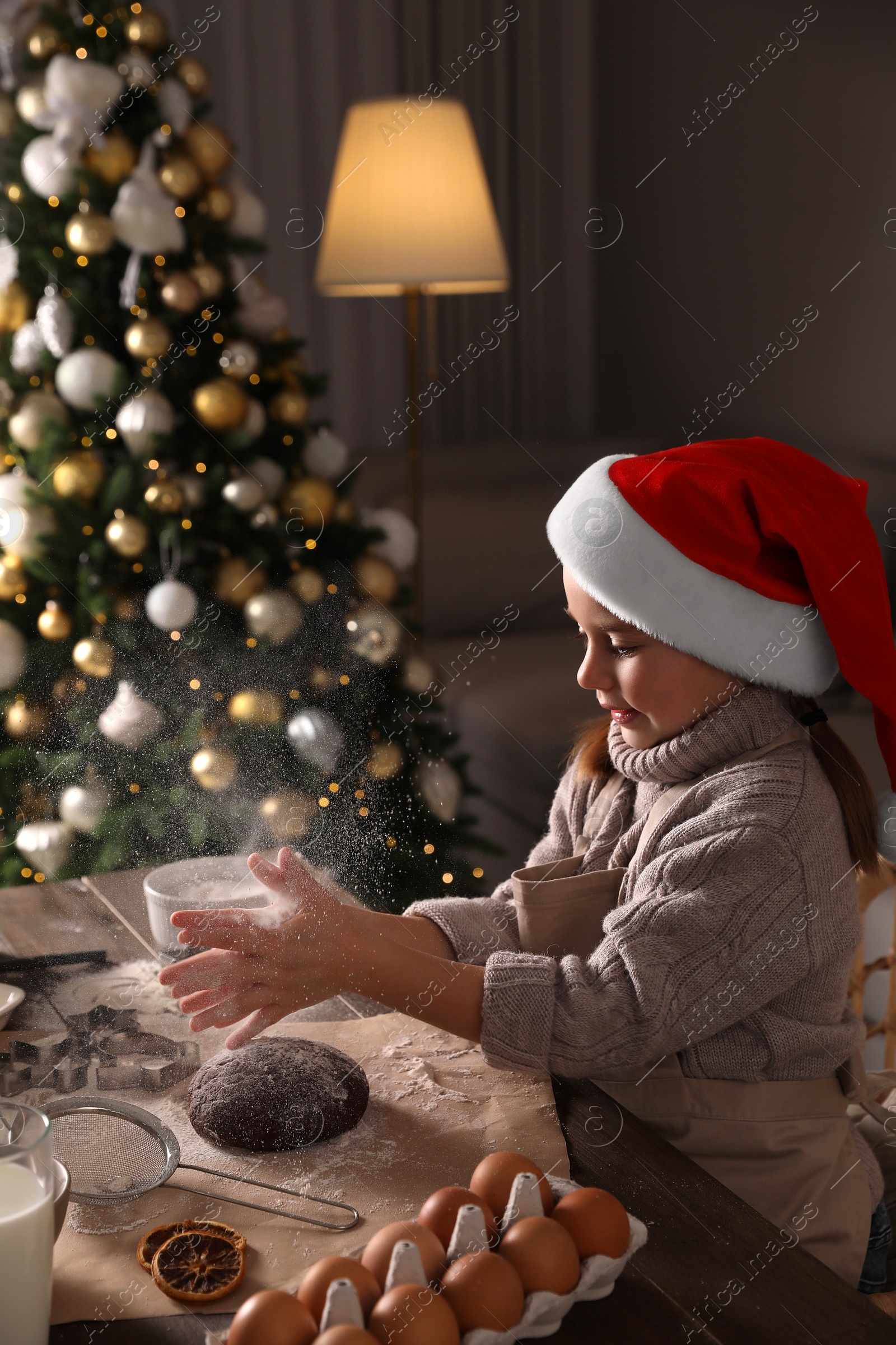 Photo of Little child in Santa hat making Christmas cookies at  home