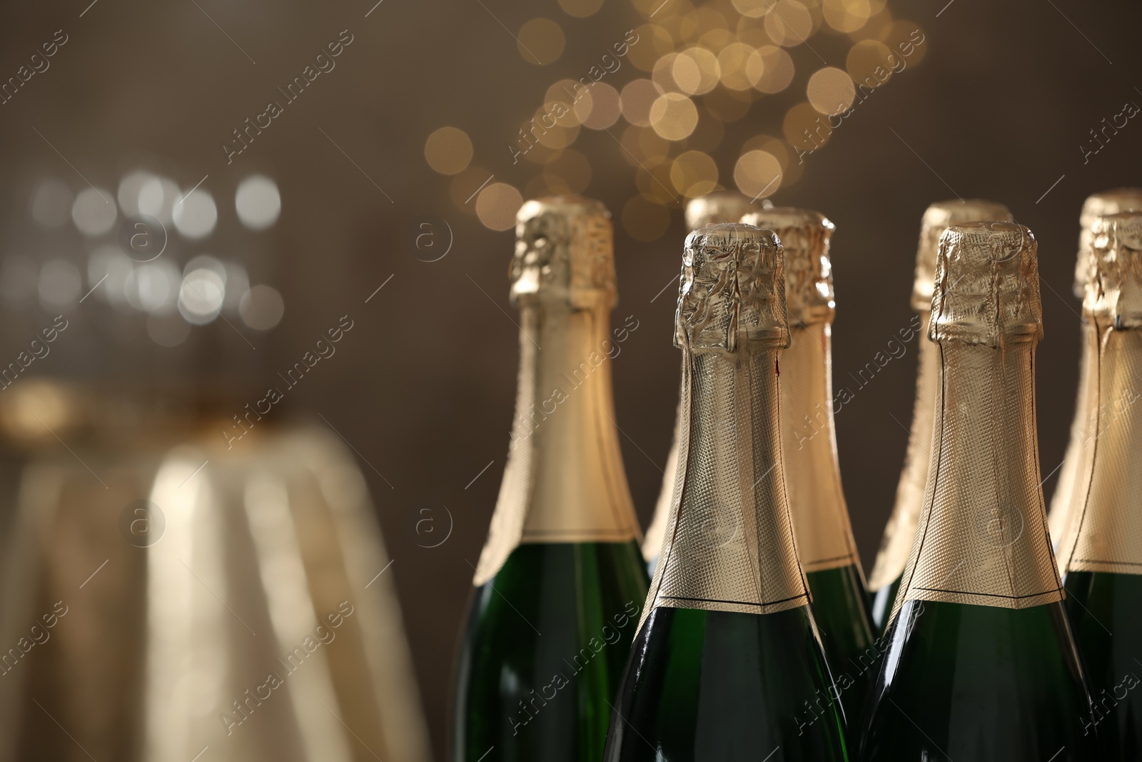 Photo of Many bottles of champagne on blurred background, closeup. Space for text