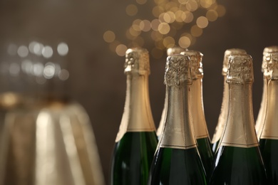 Many bottles of champagne on blurred background, closeup. Space for text