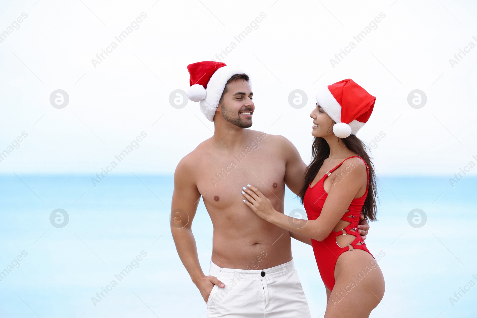 Photo of Happy young couple with Santa hats together on beach