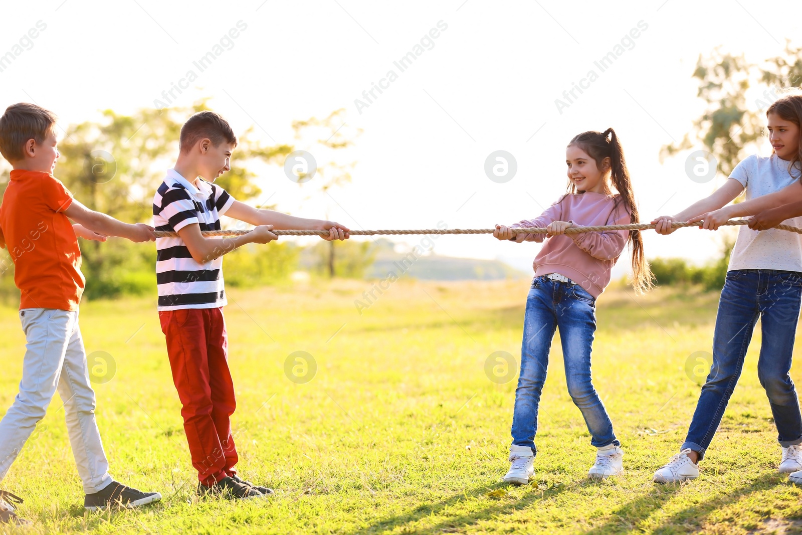 Photo of Cute little children playing with rope outdoors on sunny day