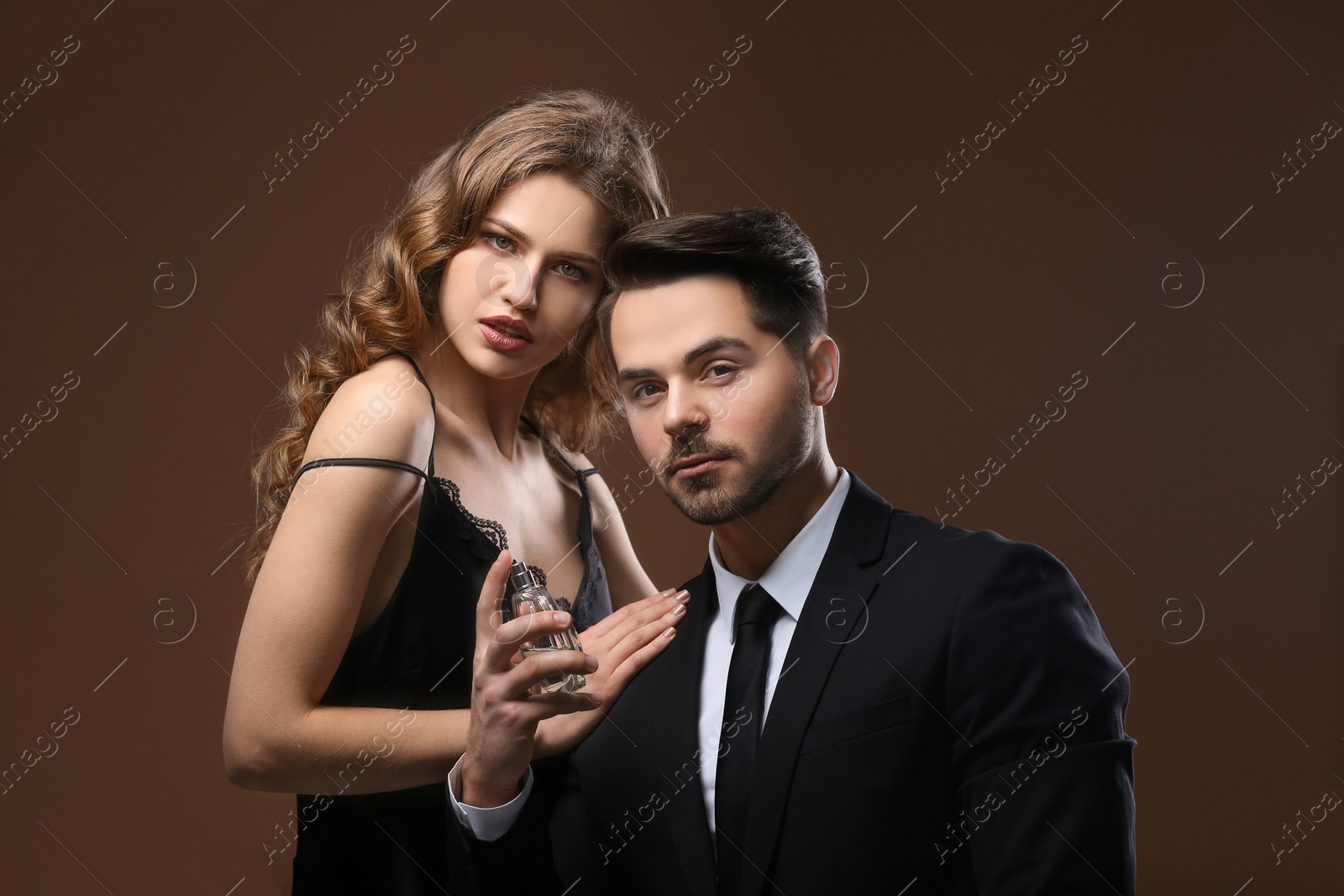 Photo of Passionate woman and handsome man using perfume on color background