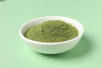 Photo of Wheat grass powder in bowl on green table