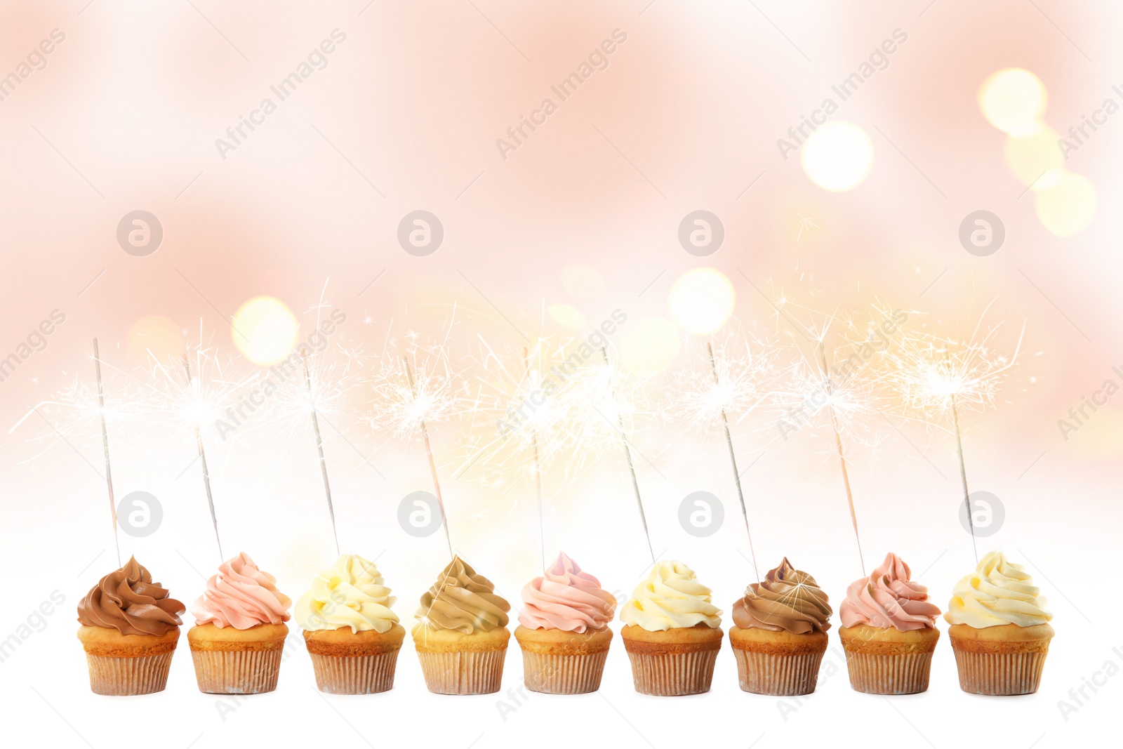 Image of Birthday cupcakes with sparklers on light background