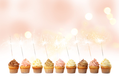 Birthday cupcakes with sparklers on light background