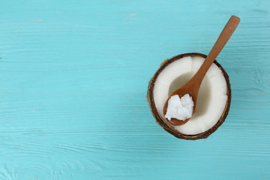 Half of ripe coconut and organic oil on light blue table, top view with space for text. Healthy cooking