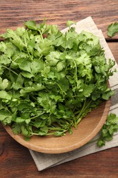 Fresh coriander in bowl on wooden table, top view